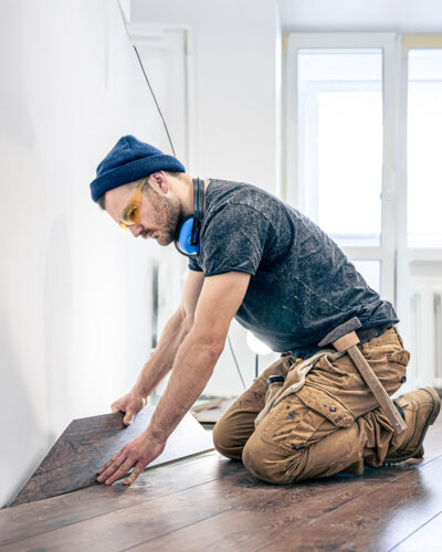 A male worker puts laminate flooring on the floor.